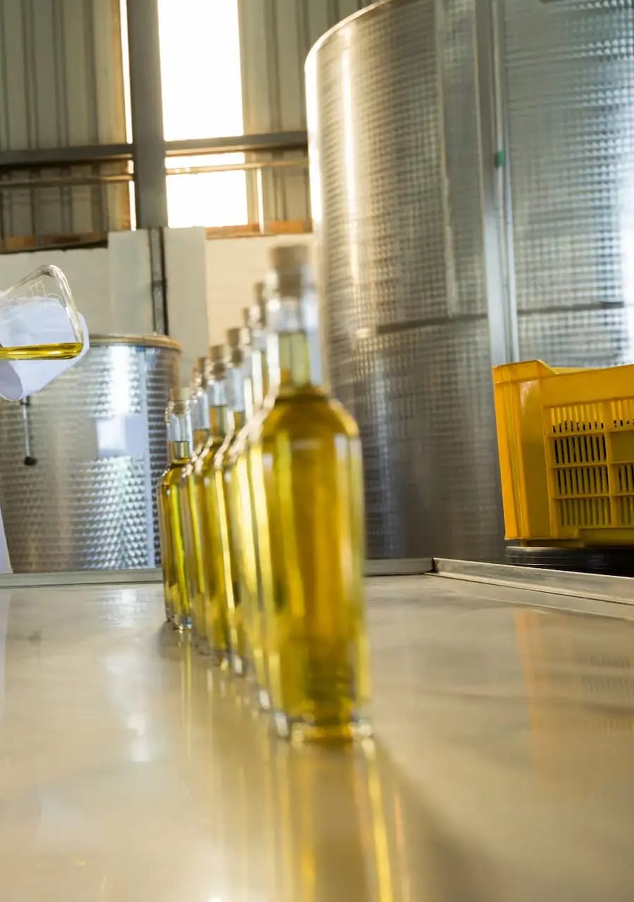 Bouteilles d’huile en attente de contrôle, citernes inox en arrière-plan